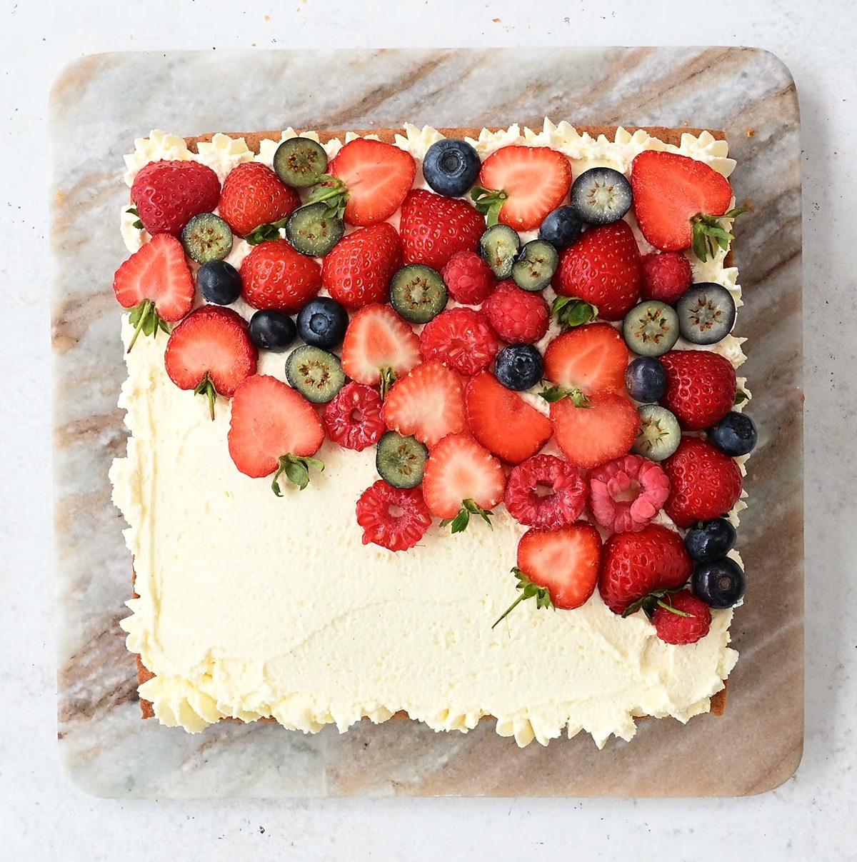 decorating sponge cake with whipped cream and fresh berries