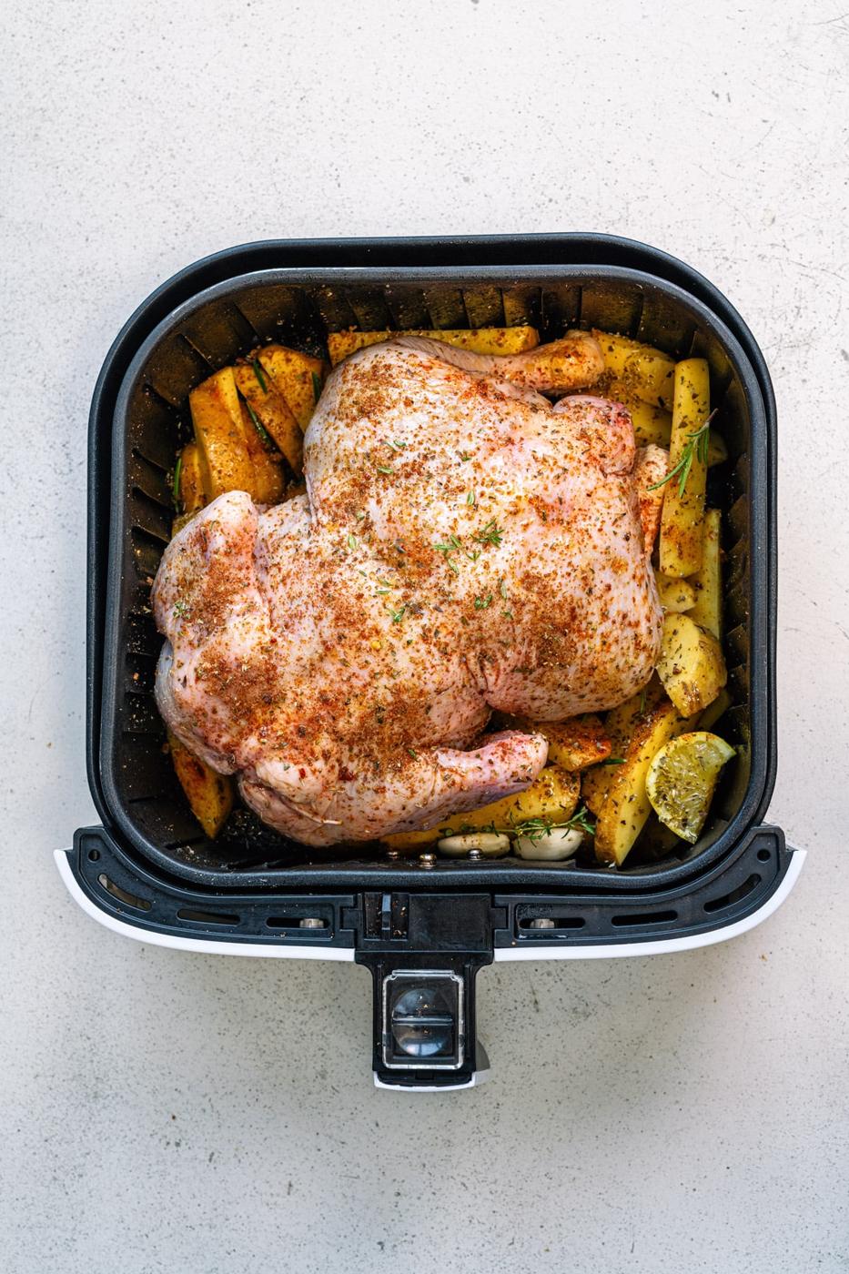 Whole raw chicken breast side down in an air fryer basket