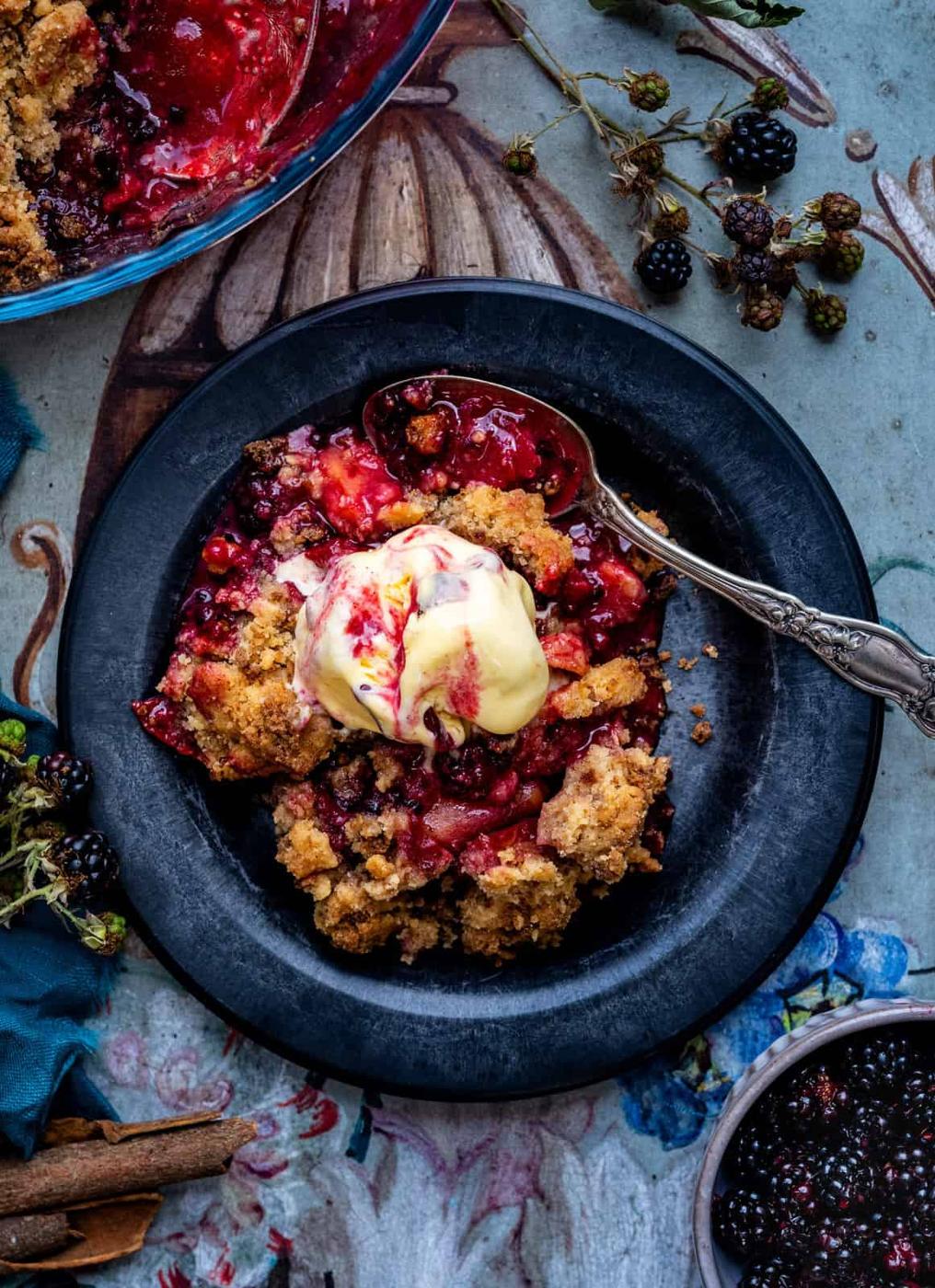 Serving of vegan blackberry apple crumble with ice cream