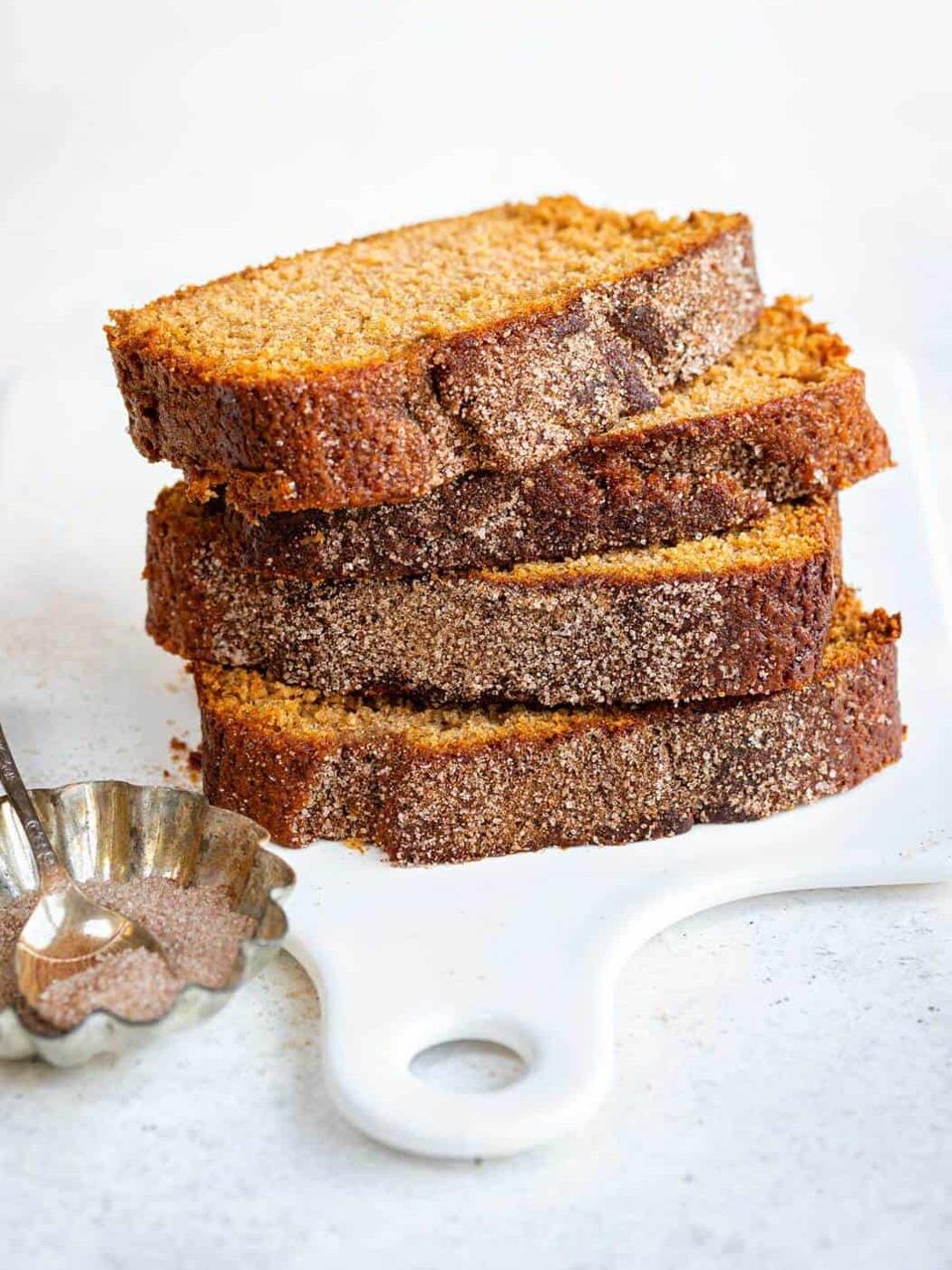 Moist cinnamon sugar loaf cake on white cutting board with sugar spoon, homely baked dessert.