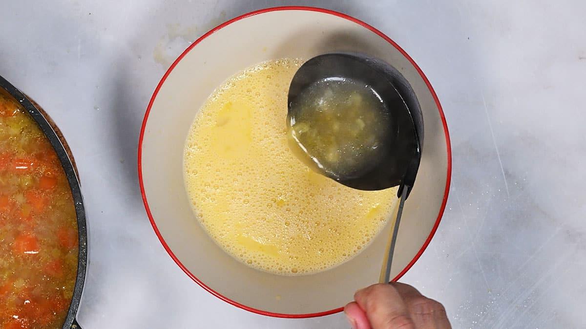 adding hot soup into avgolemono