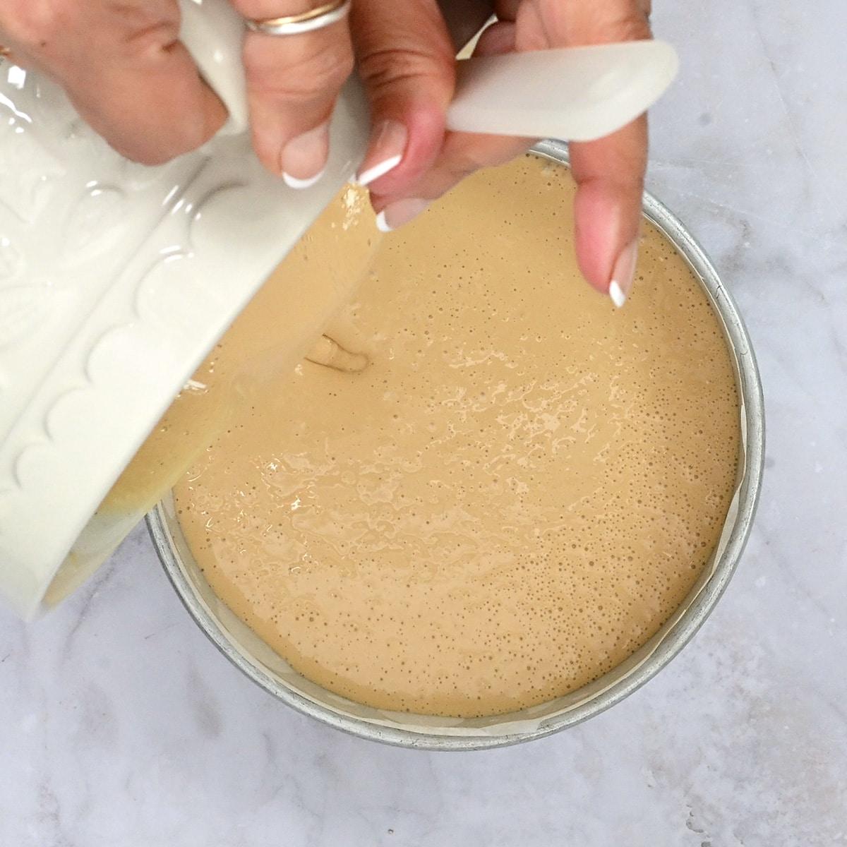 pouring cheesecake filling over crust into a pan
