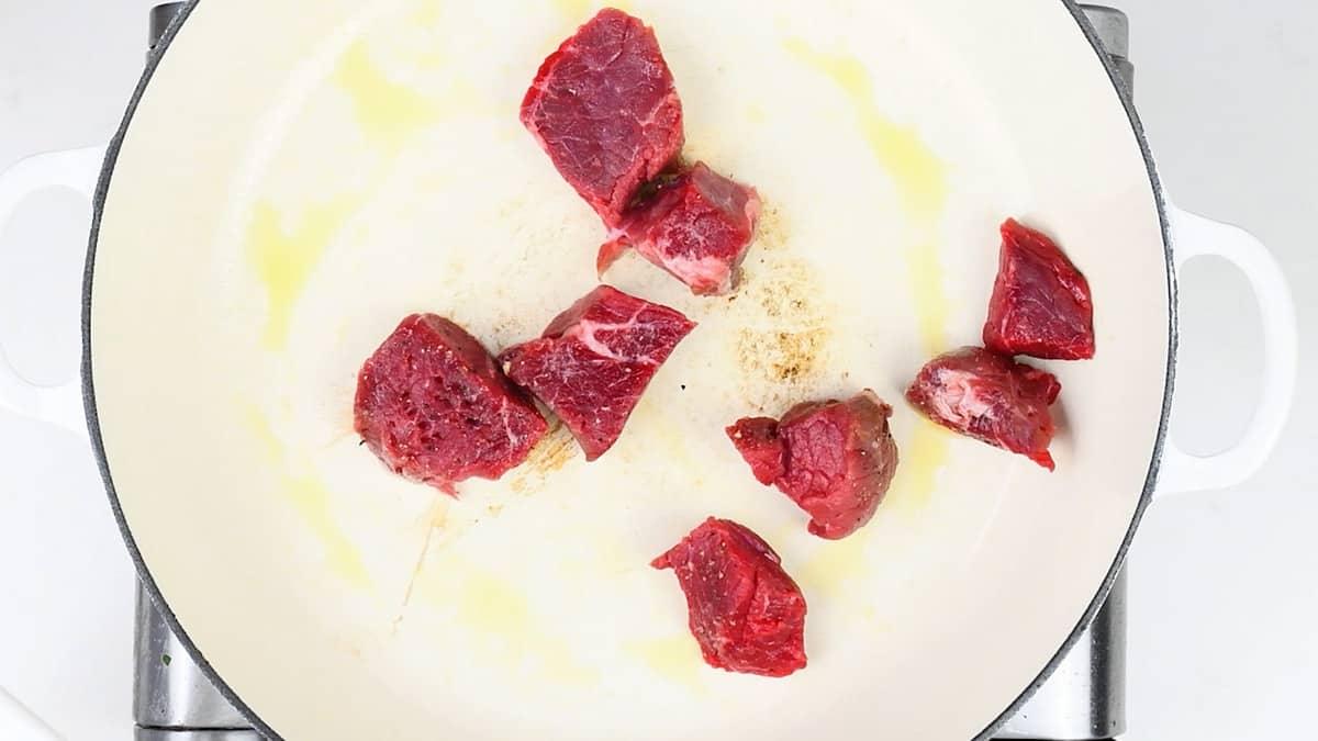 searing beef cubes in a hot pan
