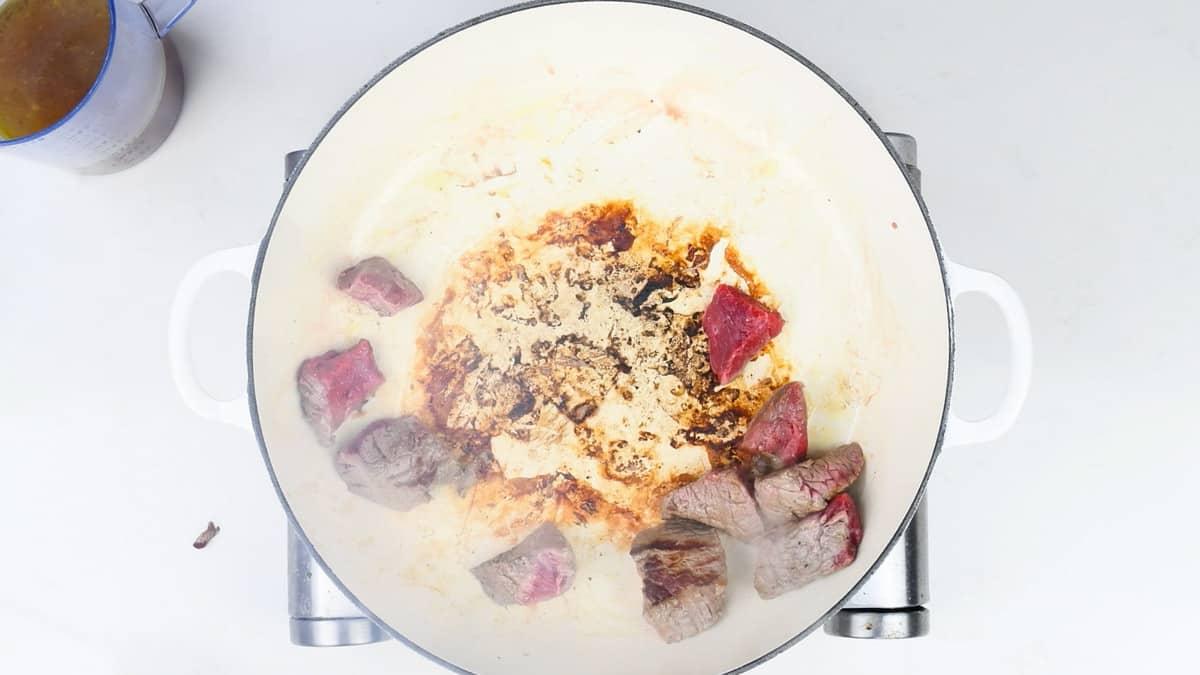 Searing beef cubes in a casserole dish for beef stew