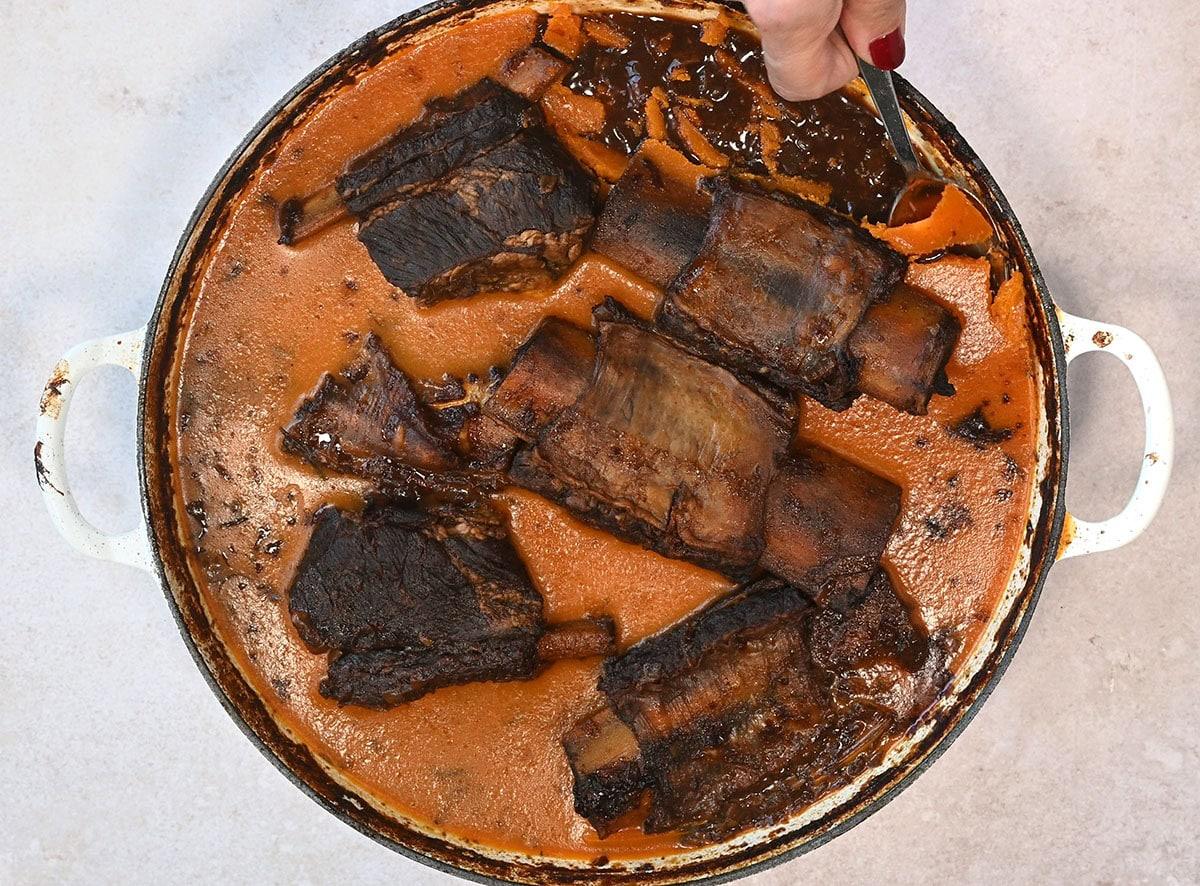skimming the fat off braised short ribs