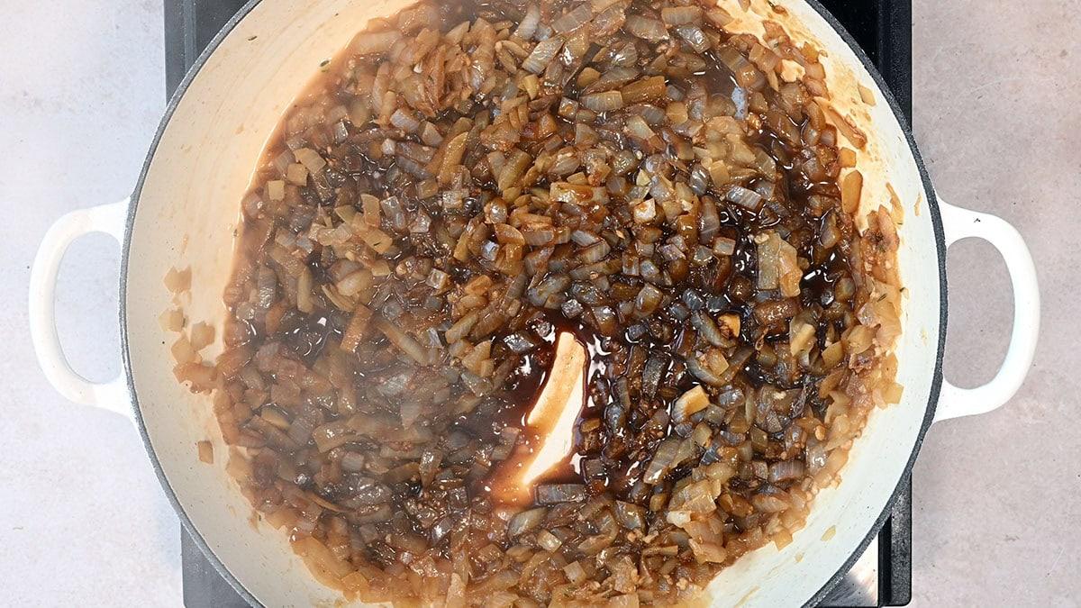 caramelised onions cooking in a skillet with red wine