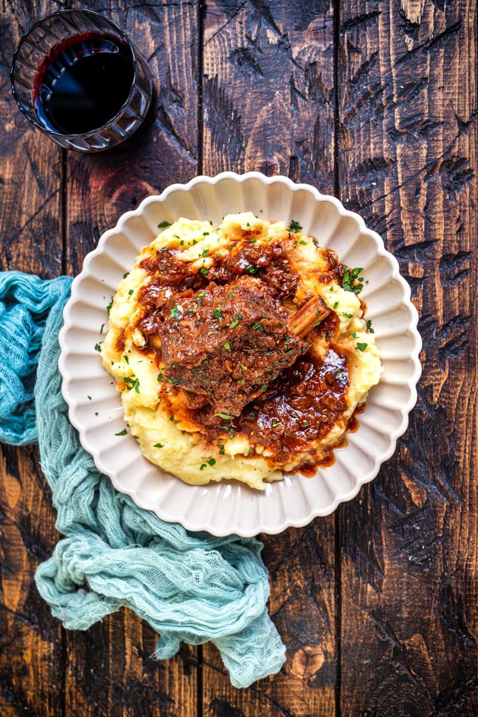 braised beef short rib served over mashed potatoes, glass of red wine on the side