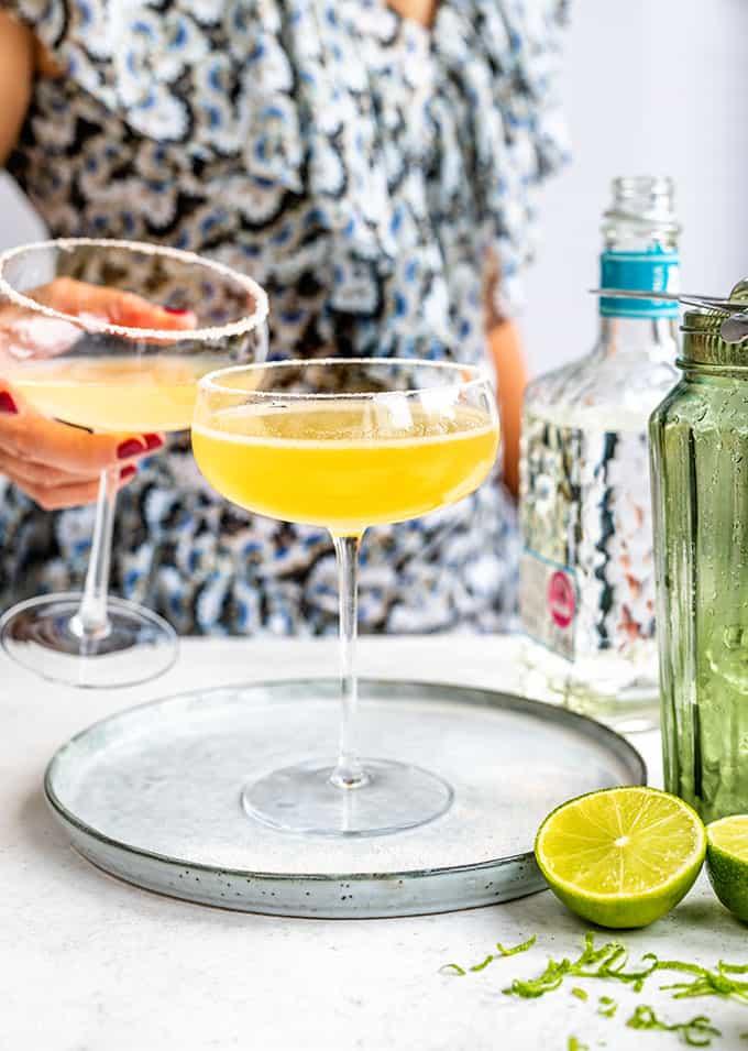 Cadillac Margaritas in a coupe glass with person in background