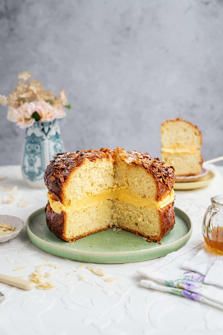 Large Bienenstich cake on a plate with big slice cut out to show the filling