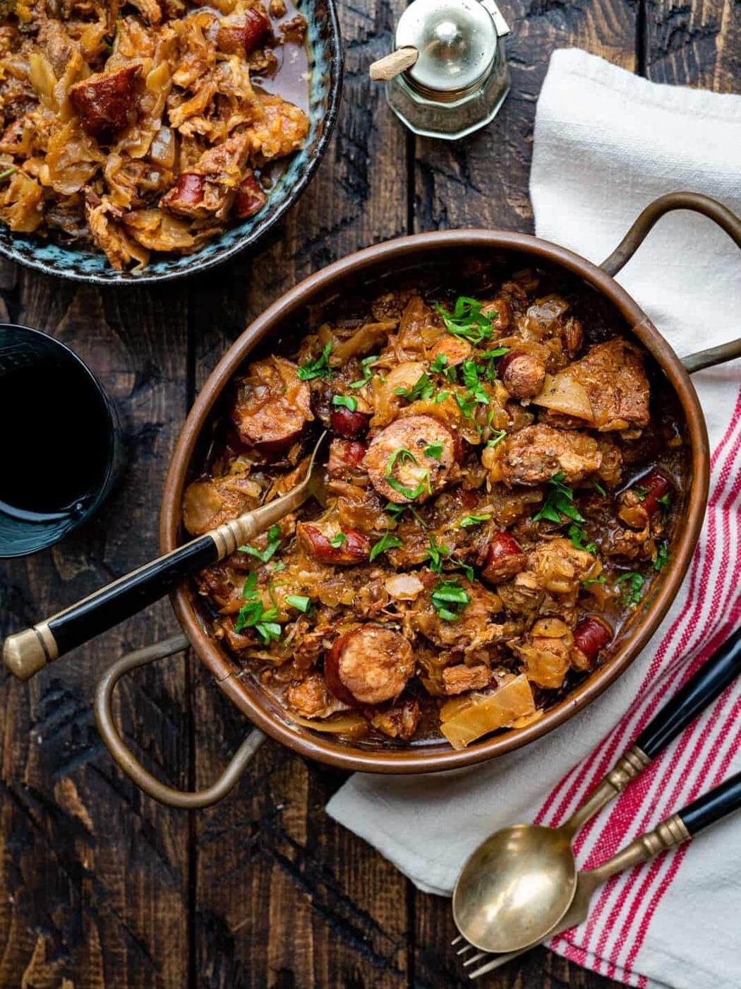 Polish Bigos Stew in a rustic copper casserole with a serving on the side