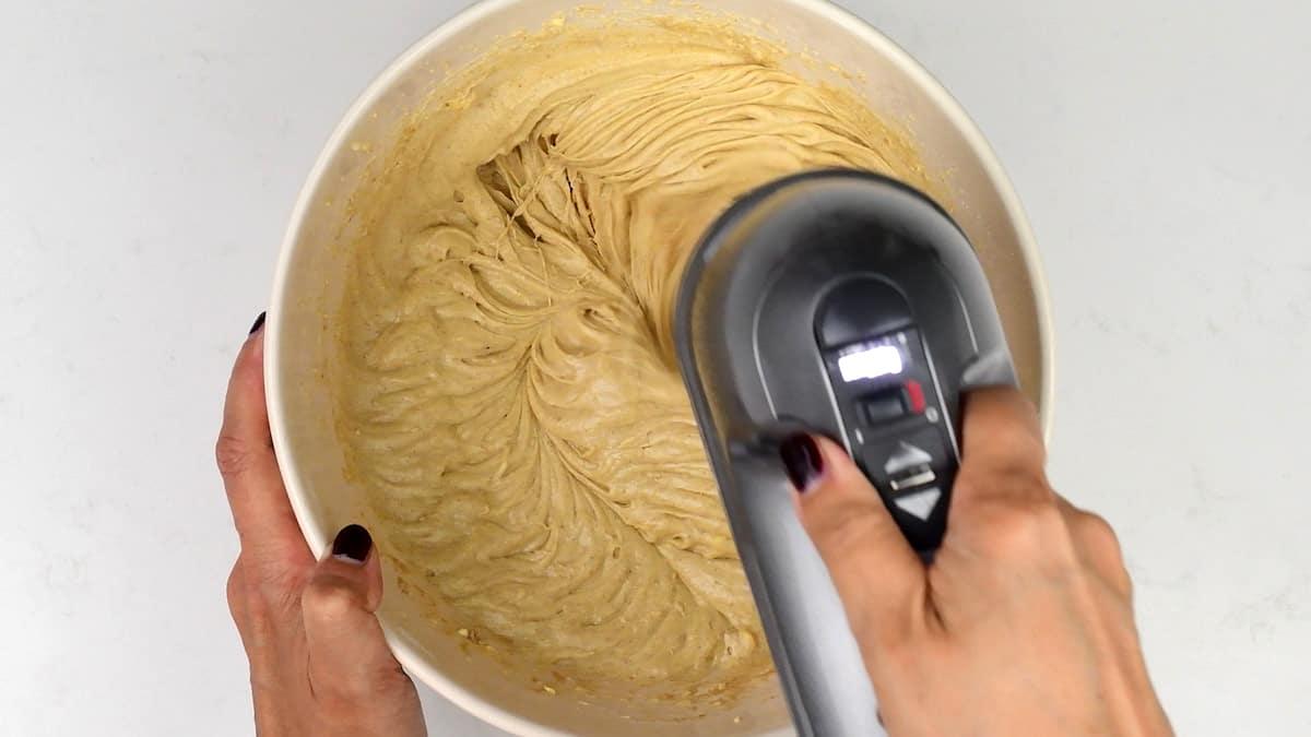 beating Biscoff cake batter in a bowl with an electric hand mixer