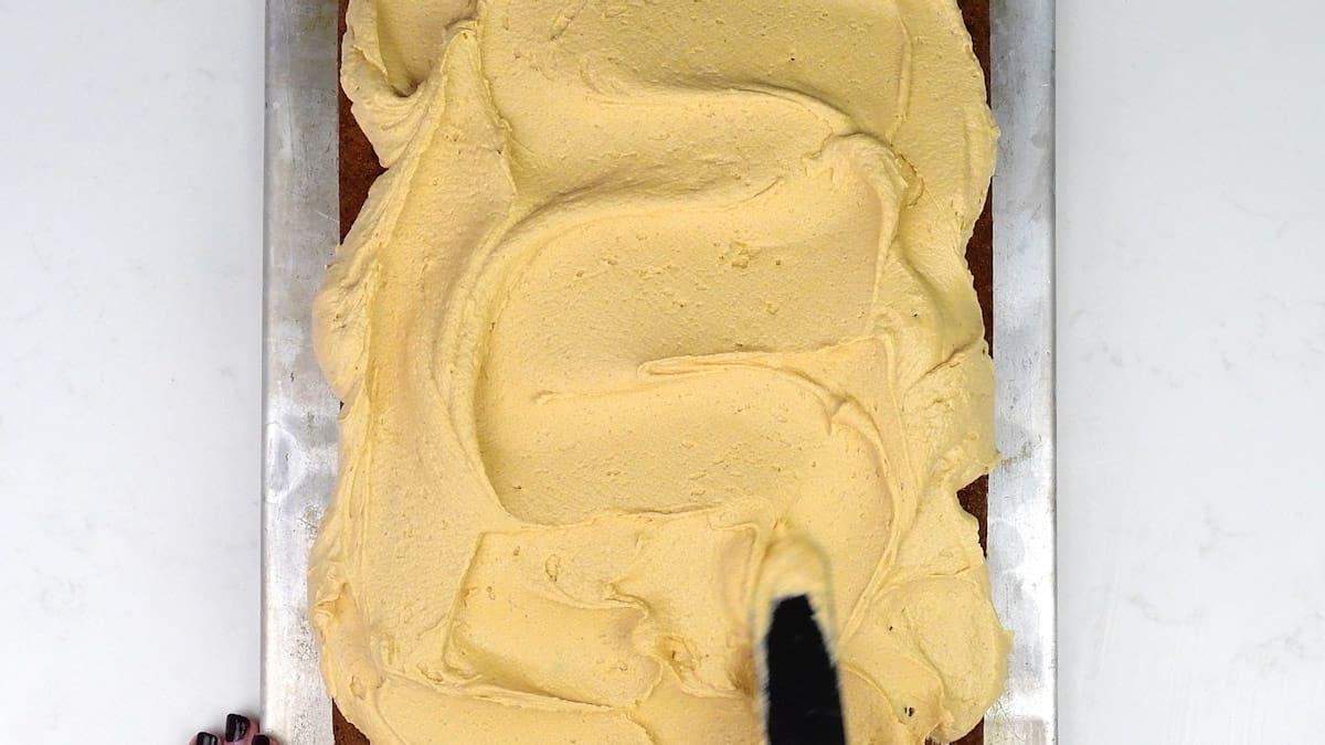 spreading a Biscoff traybake cake with speculcoos cookie buttercream