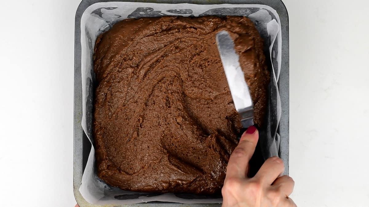 Spreading fudge in a lined square tin