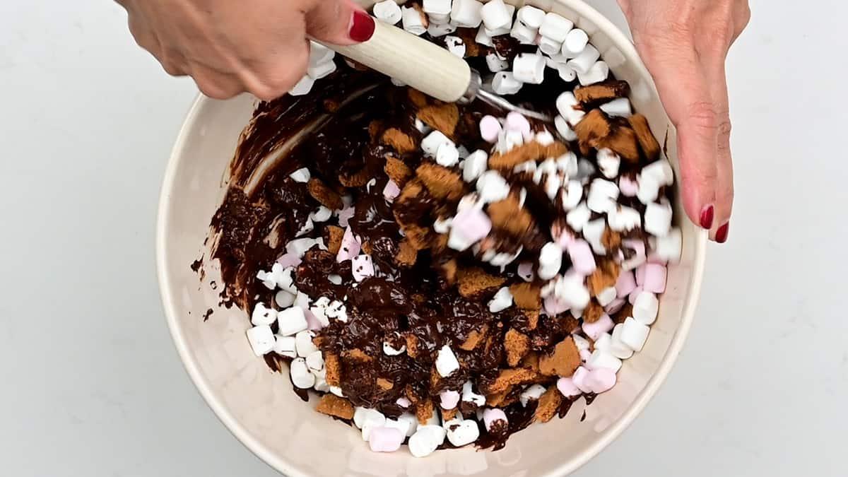 Stirring marshmallows and Biscoff cookies into melted chocolate