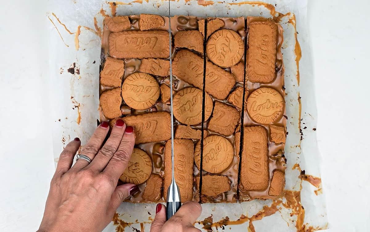 slicing Biscoff Rocky road with a large knife