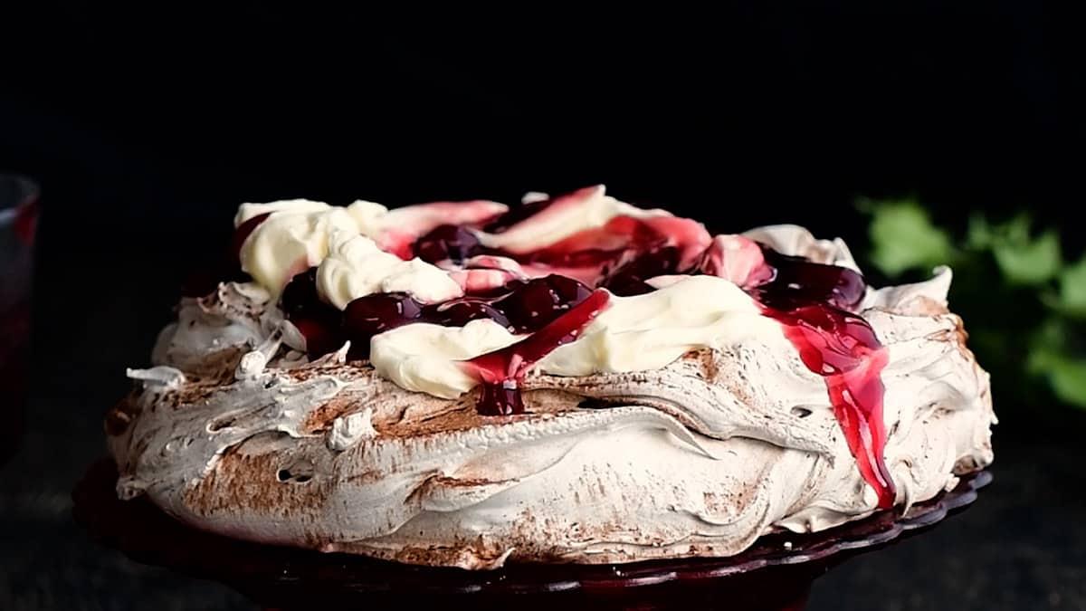 layering Black Forest pavlova with whipped cream and cherries