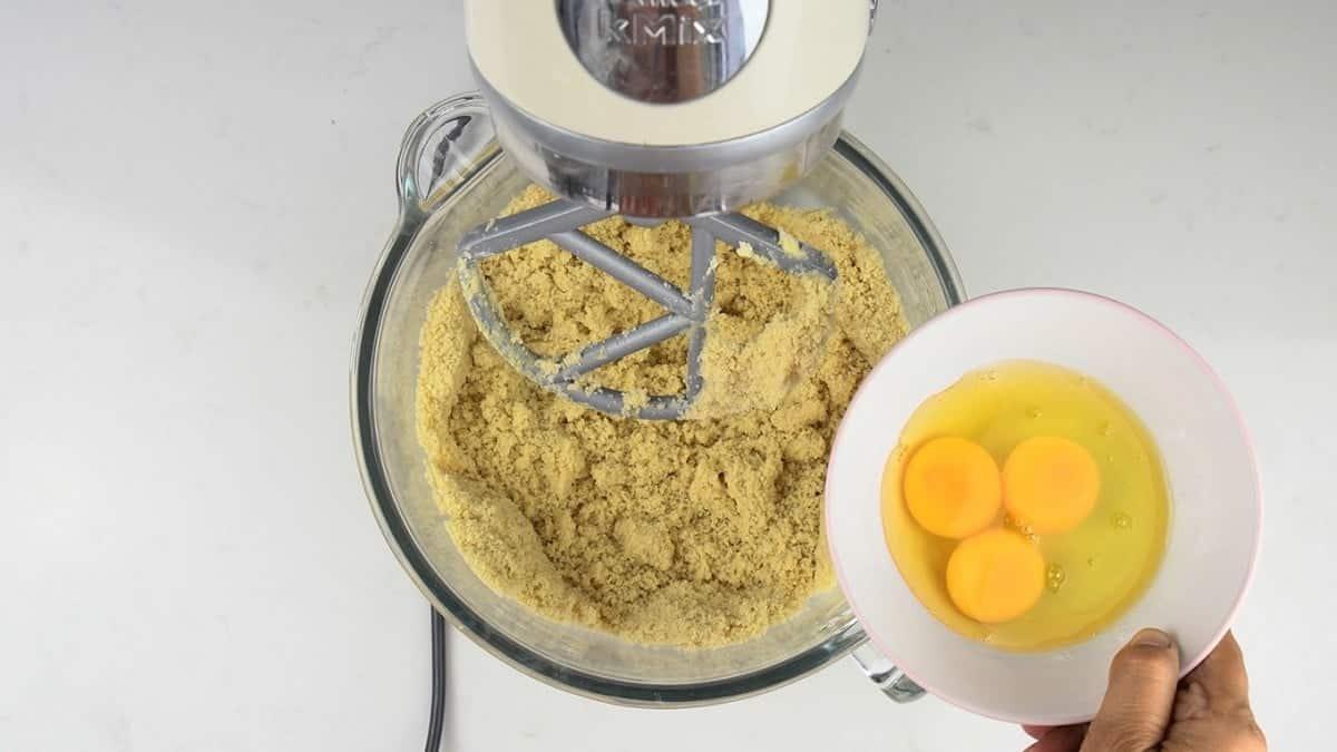 Adding eggs to the batter of a blueberry bundt cake