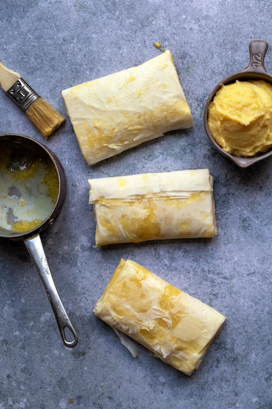Greek Bougatsa hand pies ready to be baked, bowl of semolina custard on the side
