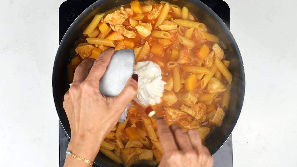 Stirring cream cheese into the cooked one-pot Cajun chicken pasta