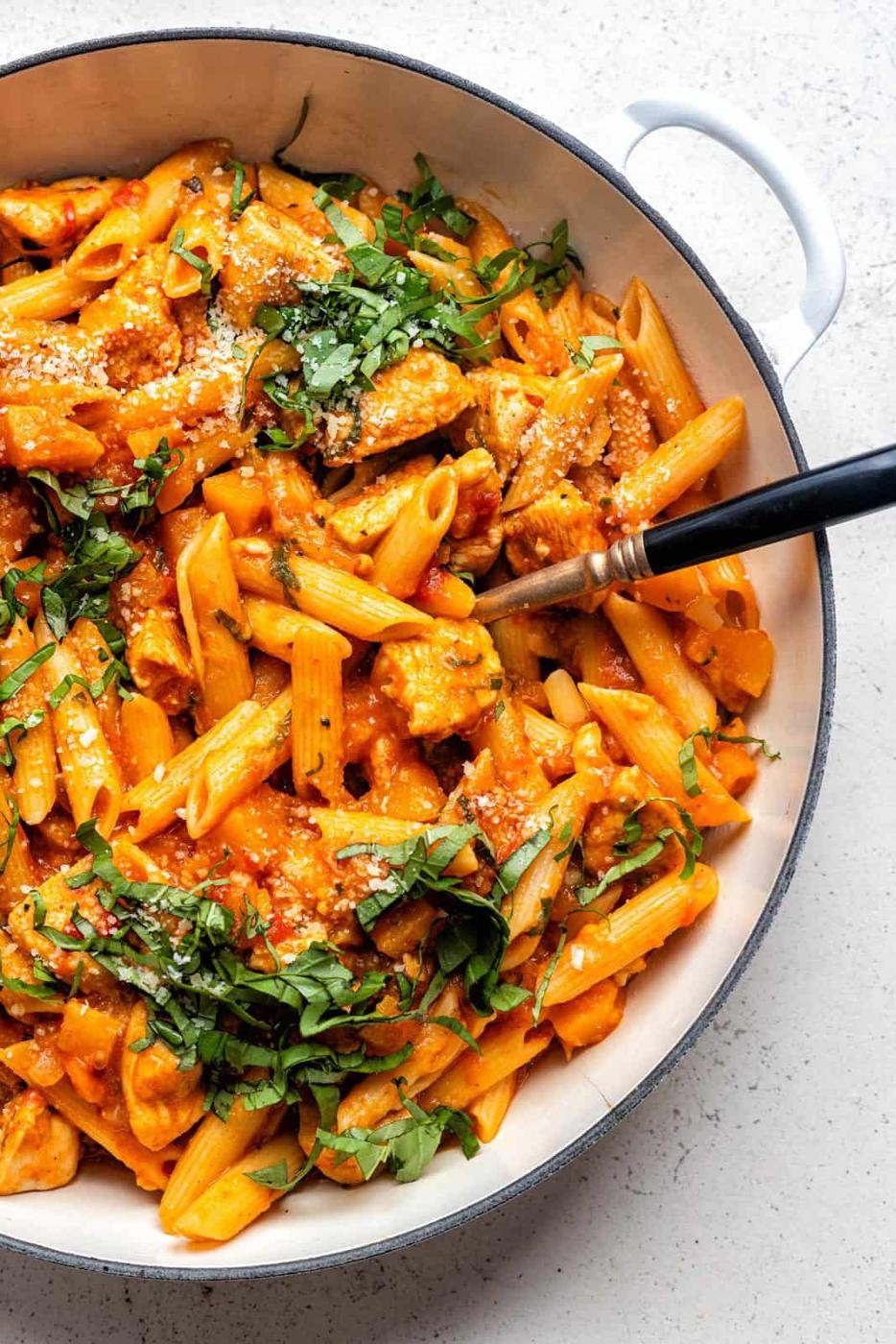 Large casserole dish with cajun chicken pasta garnished with chopped fresh basil