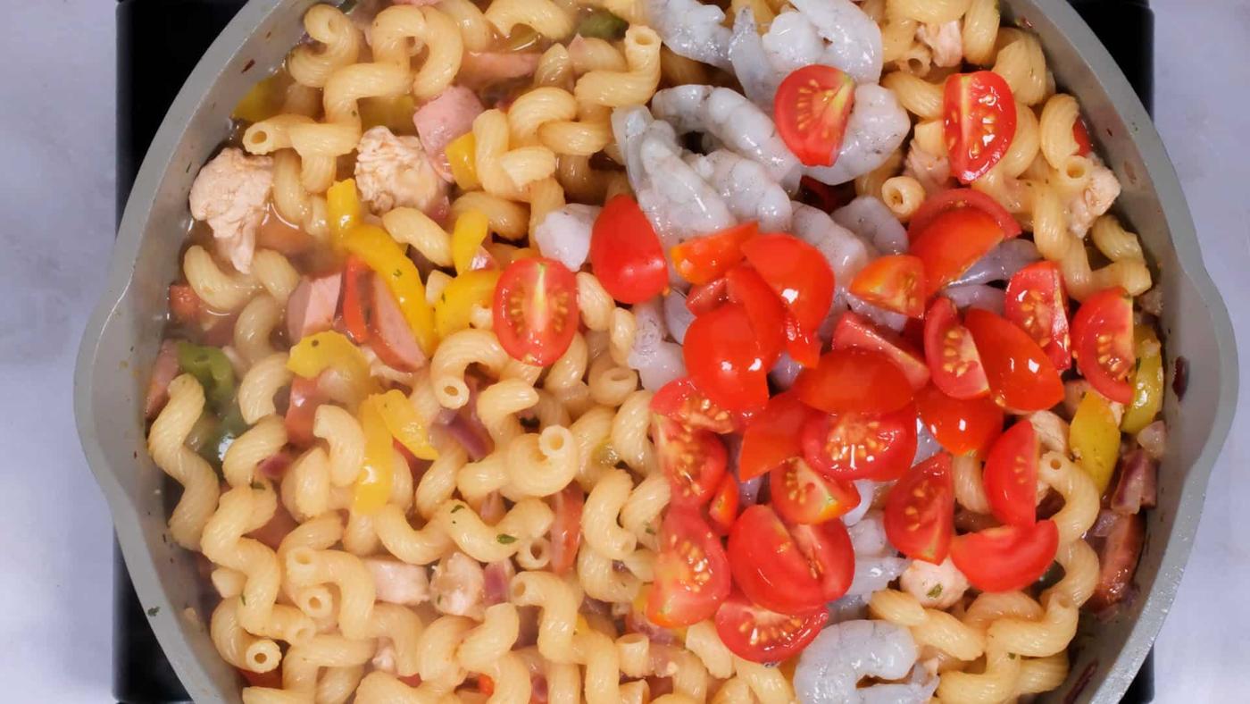 pasta with shrimp, chicken, sausage, Cajun seasoning and vegetables cooking in a pan