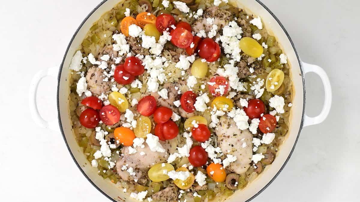 rice and chicken casserole topped with cherry tomatoes and crumbled feta cheese