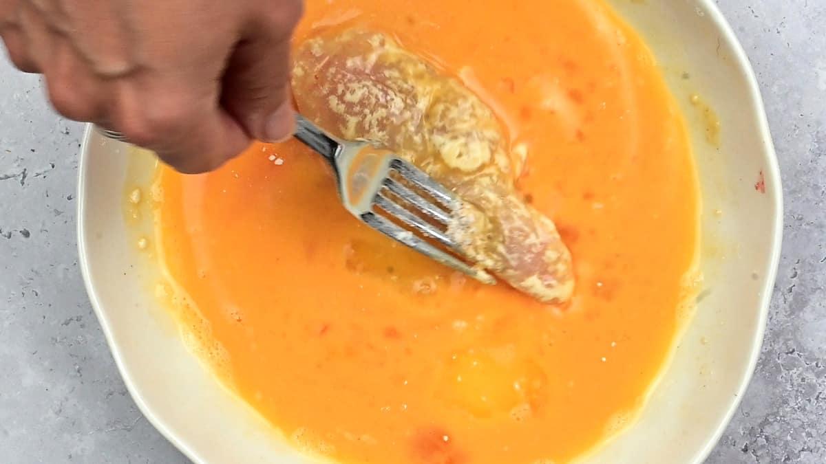 Dipping floured chicken strip into beaten egg