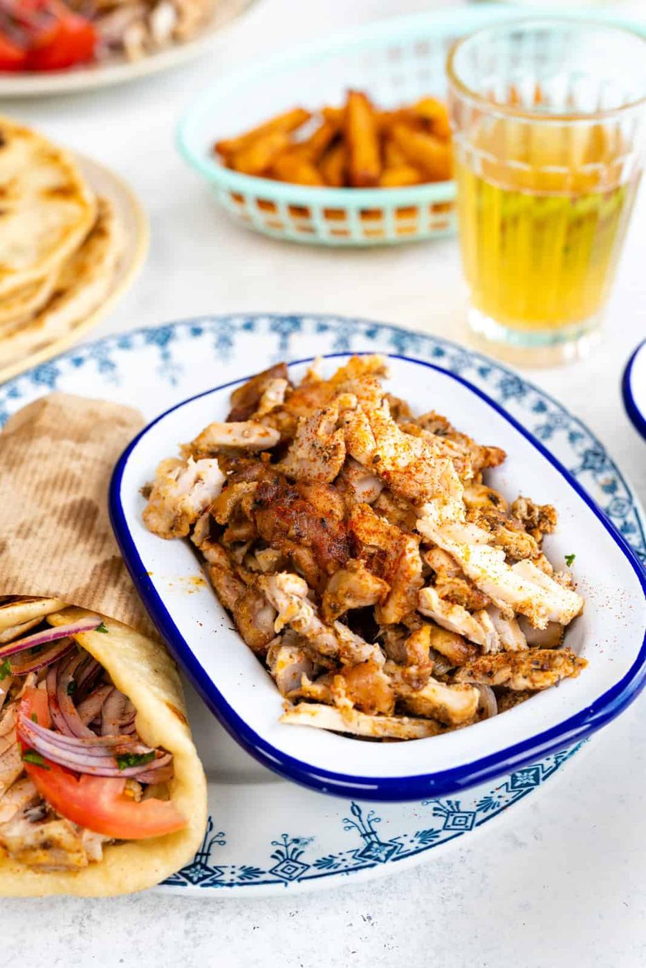 Plate with sliced chicken gyros in a bowl and gyros pita on the side