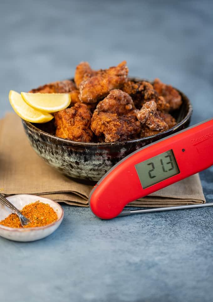 Bowl of fried chicken with a Thermapen digital thermometer propped on the side