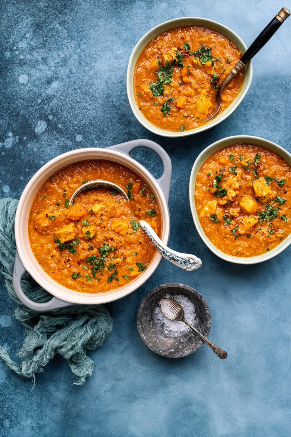Chicken and lentil soup on a blue backgroud, one small pot and two bowl servings