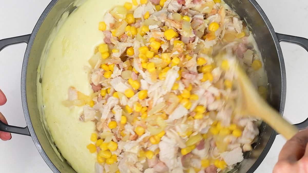 stirring chicken, bacon, corn and onion into cheese sauce
