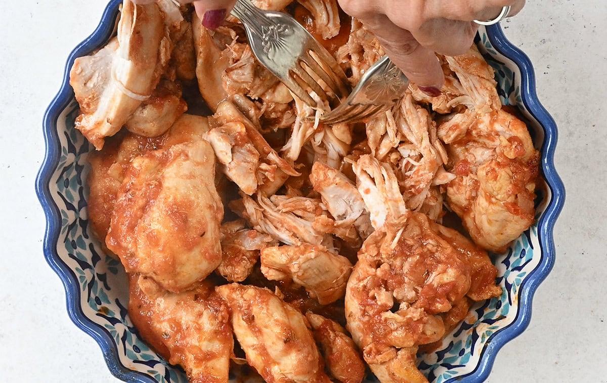 shredding cooked chicken thighs with two forks