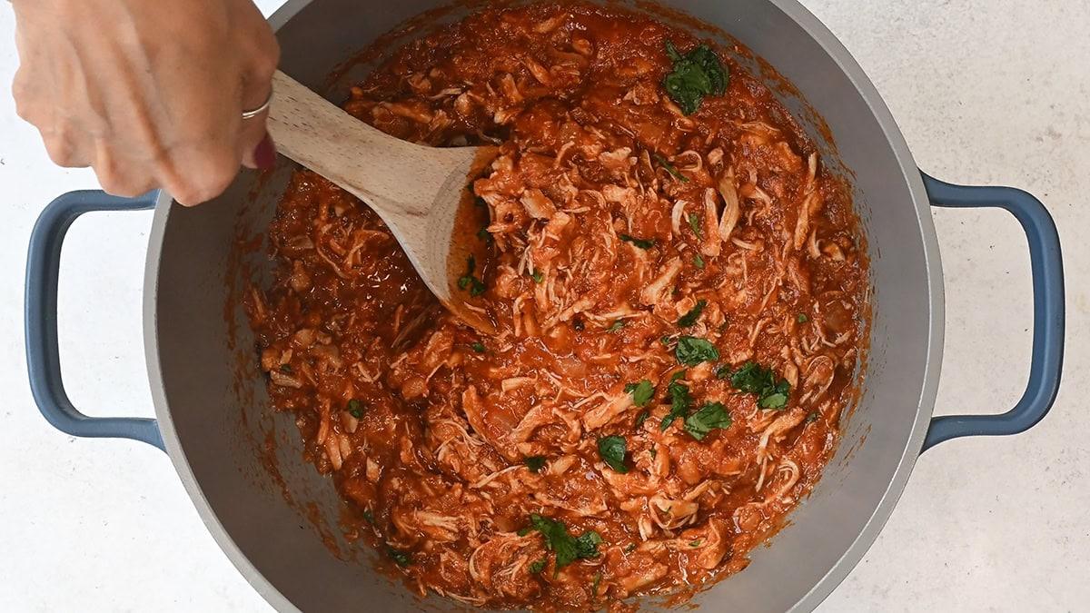 stirring a pot of shredded Chipotle chicken