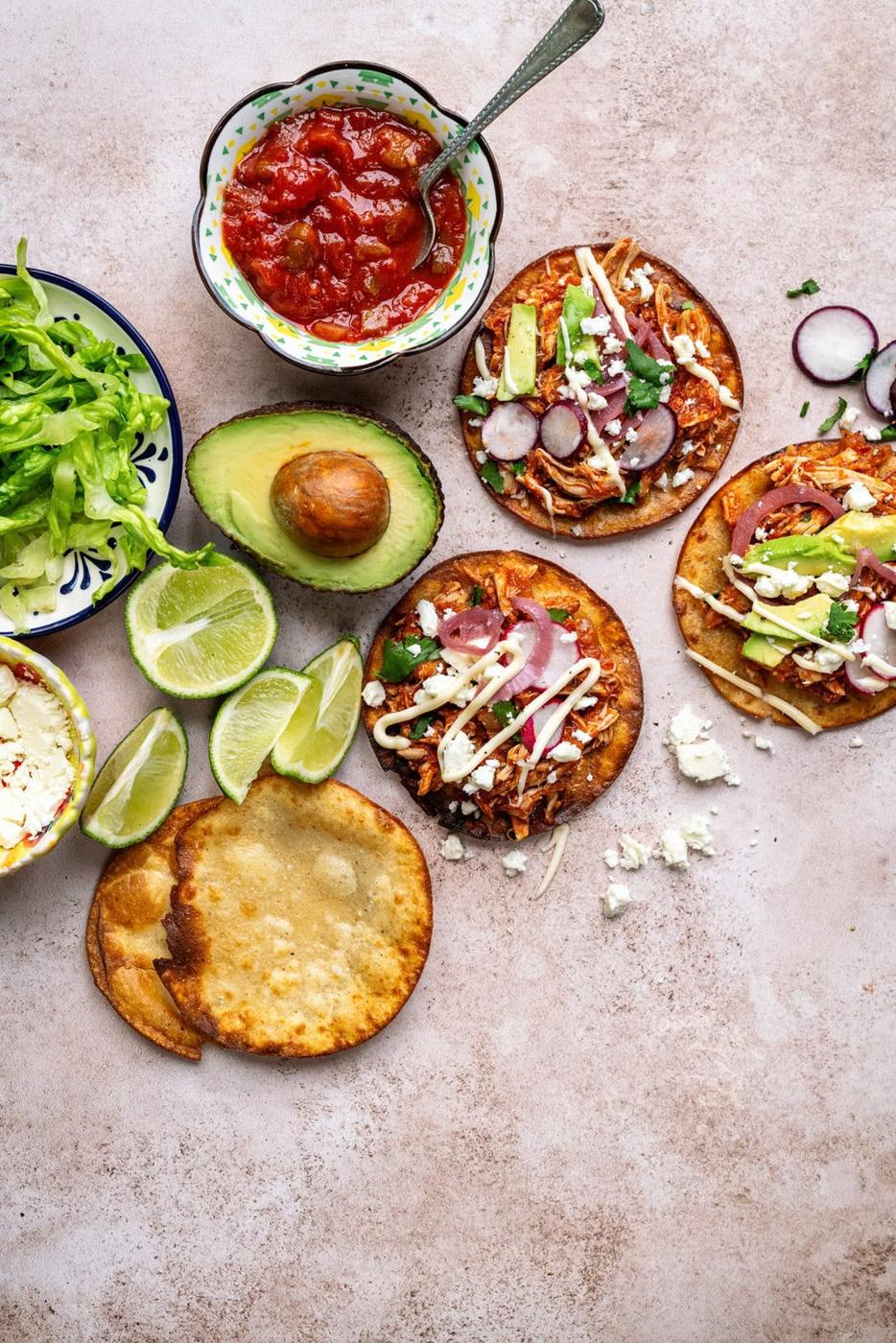 Tabletop with tostadas with chicken tinga, avocados, cheese