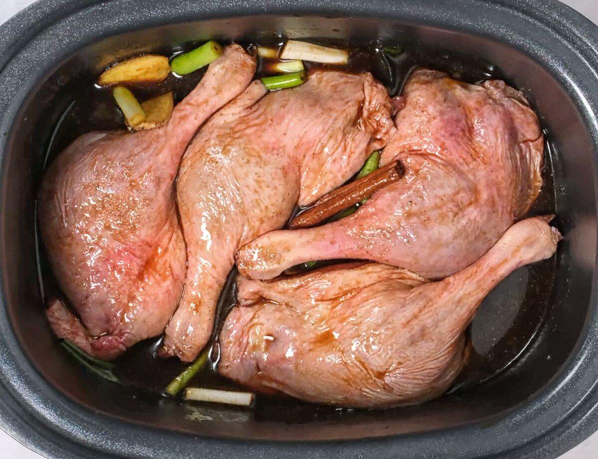 Duck legs marinating in a slow cooker insert
