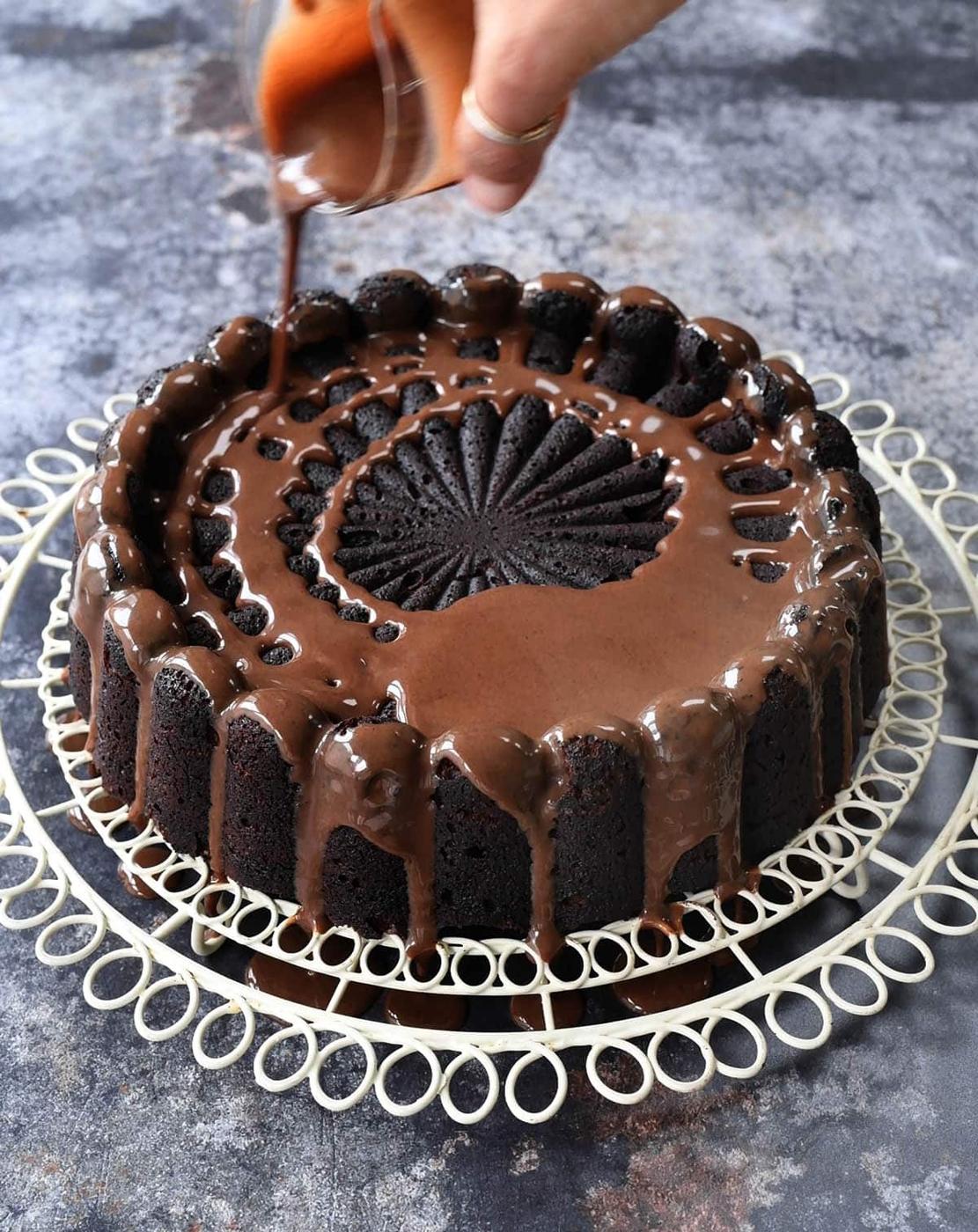 drizzling ganache over chocolate almond cake