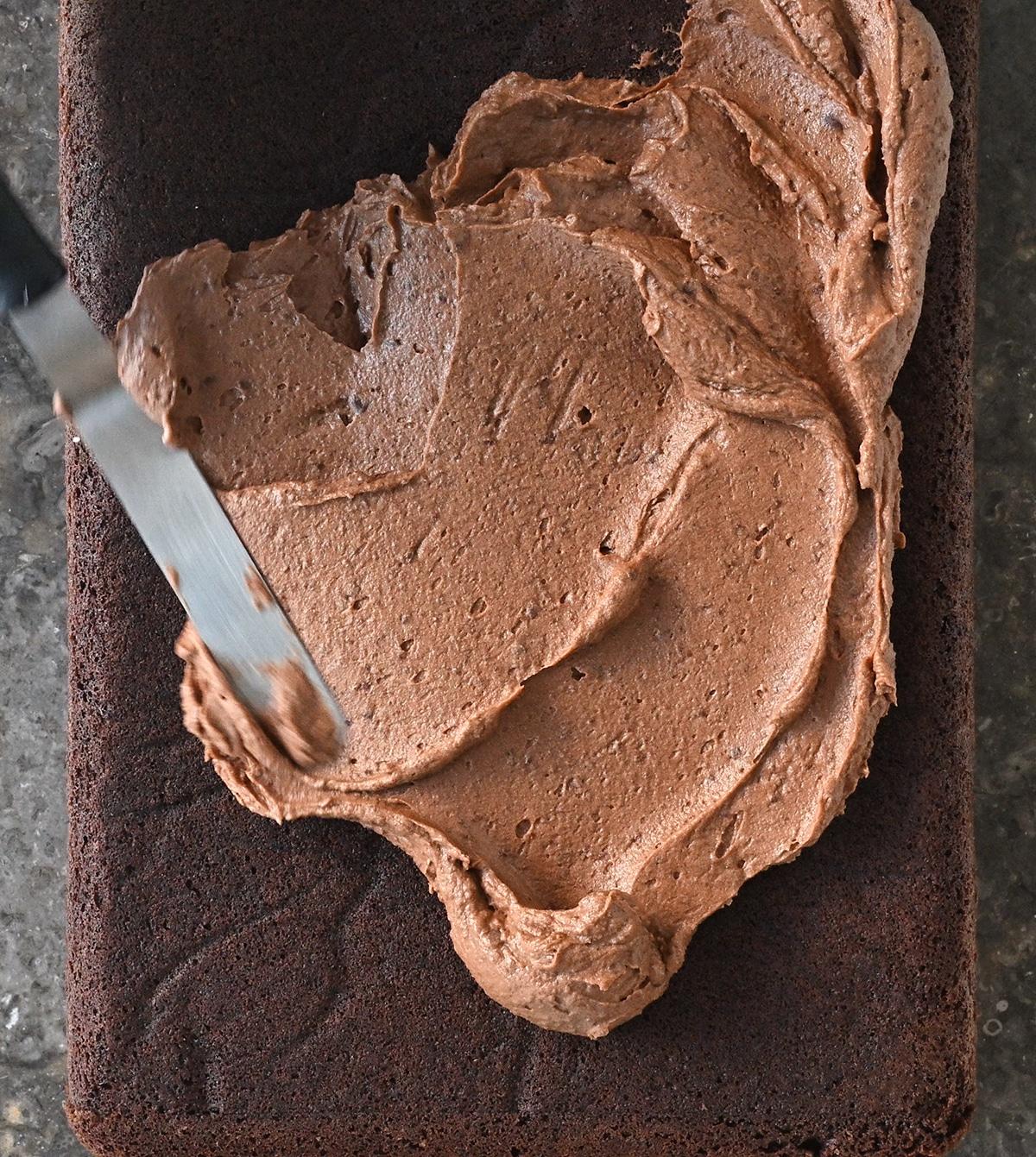 spreading chocolate frosting over chocolate banana sheet cake