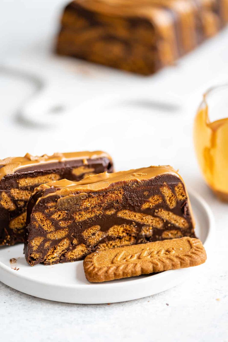 Chocolate fridge cake slices on a plate with Lotus Biscoff biscuit in foreground