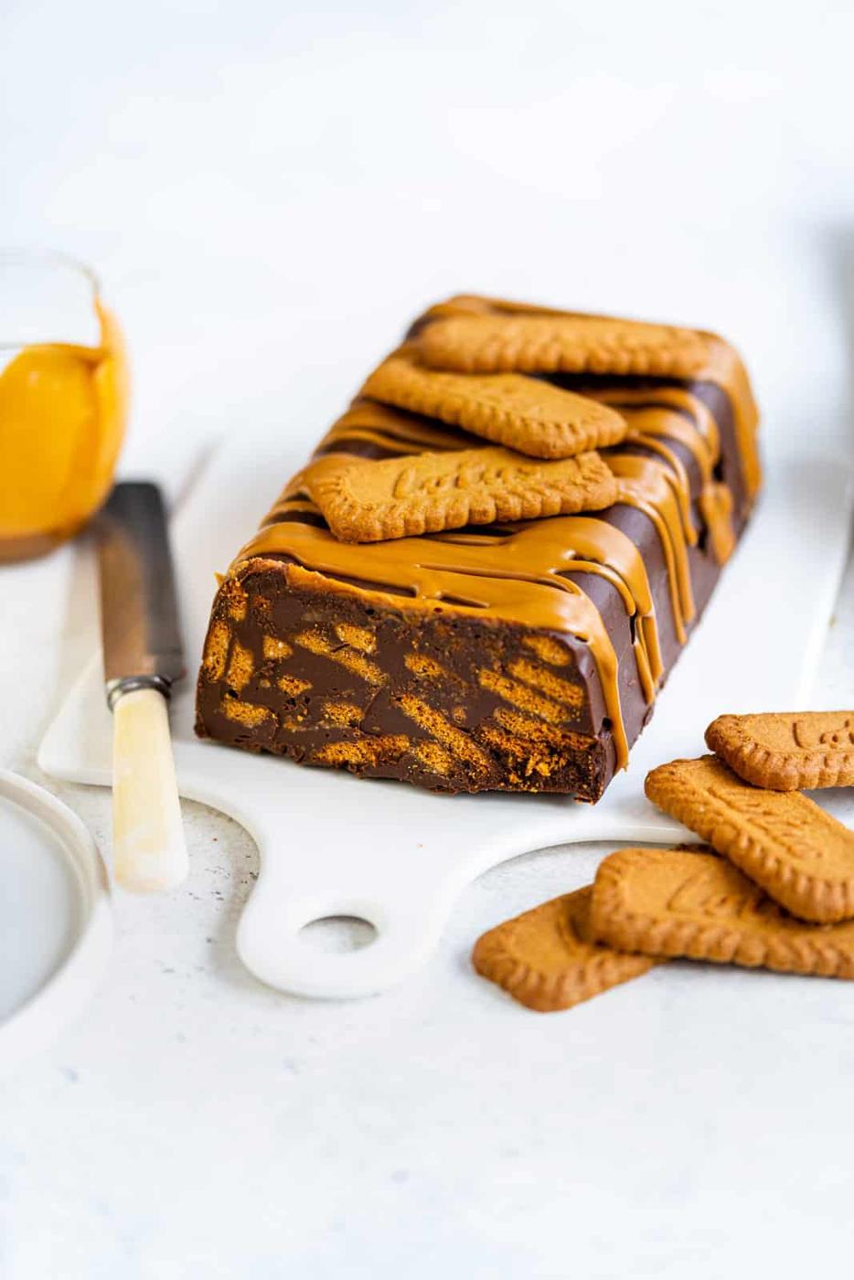 Chocolate biscuit cake topped with Biscoff cookies on a ceramic white board