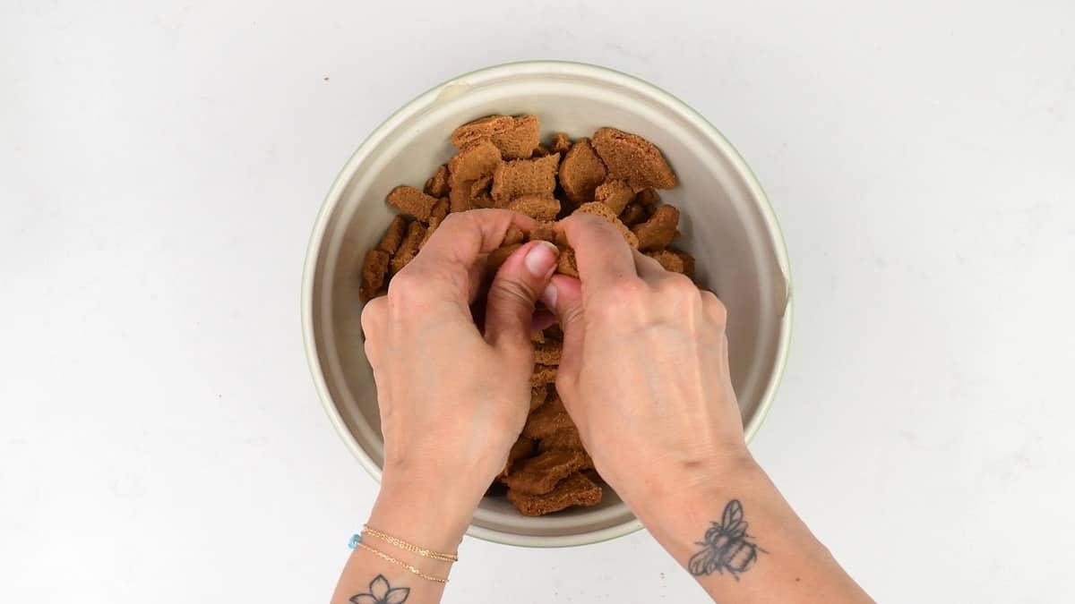 breaking Lotus Biscoff biscuits into small pieces