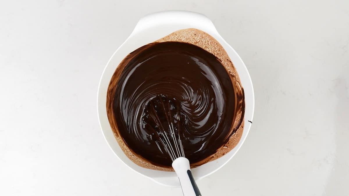 Stirring melted chocolate and butter in a bowl using a balloon whisk