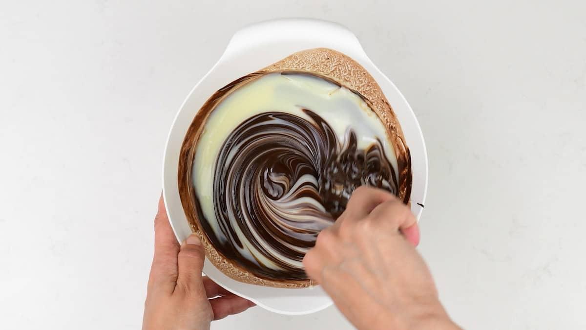 stirring condensed milk into melted chocolate in a bowl