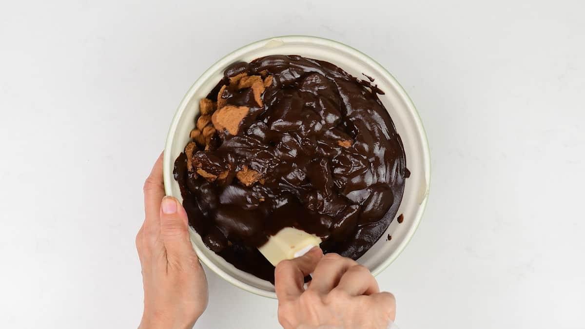 mixing chocolate and broken biscuits in a bowl to make chocolate fridge cake