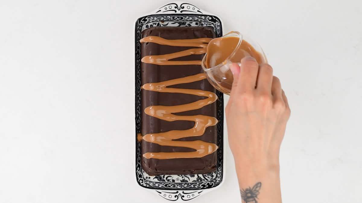 drizzling melted cookie butter spread over chilled chocolate biscuit cake