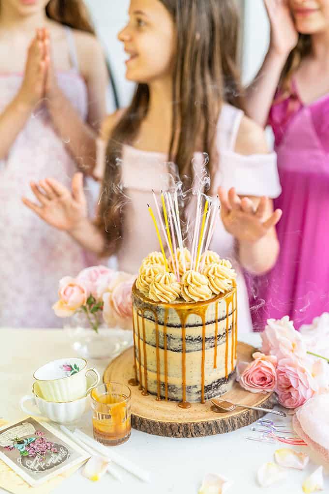 Birthday Caramel Cake with just blown out candles and girls in background