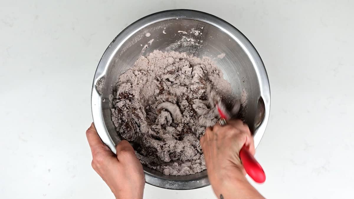 mixing egg whites into almond flour, icing sugar and cocoa using a spatula