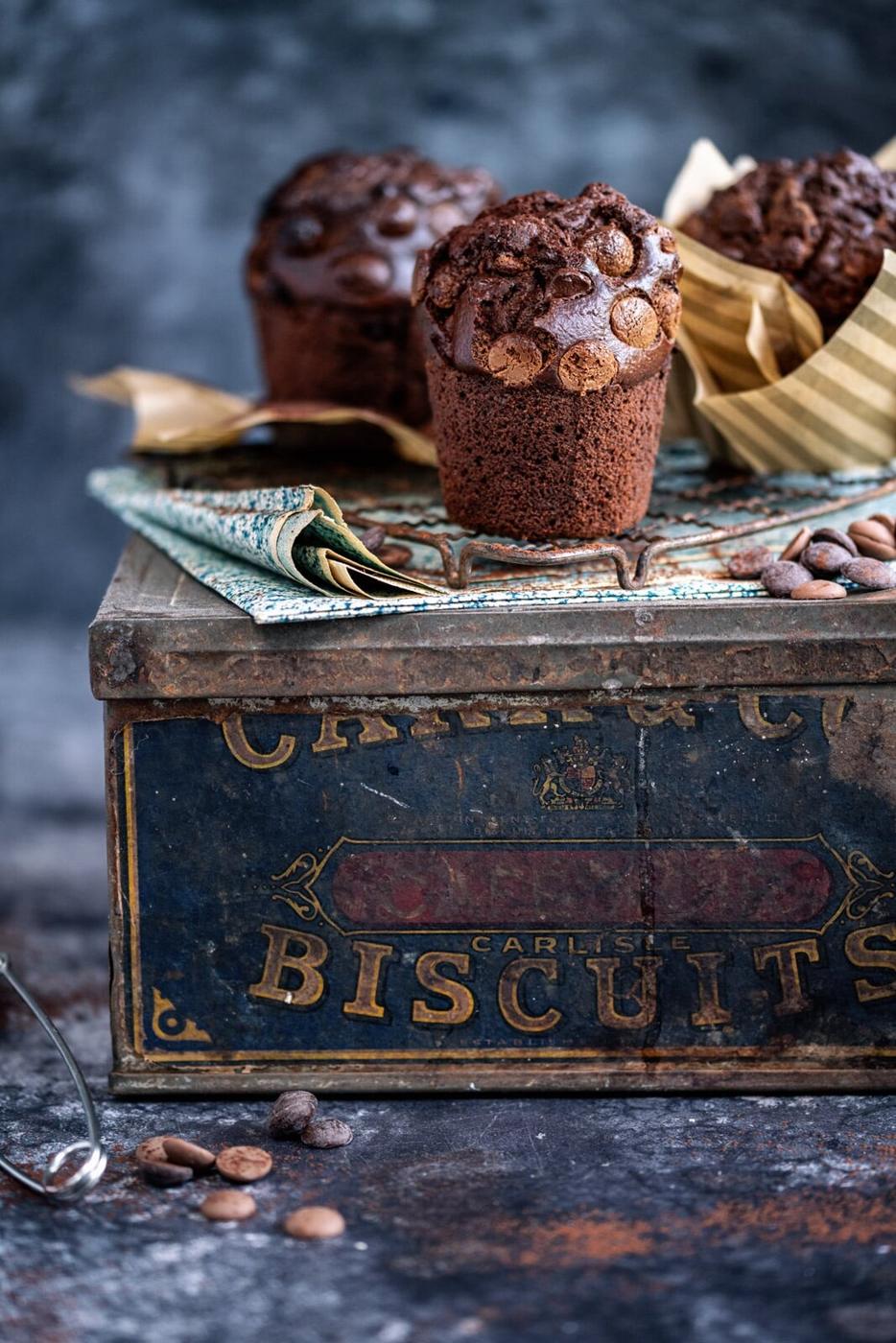 three chocolate muffins on top of a vintage metal box