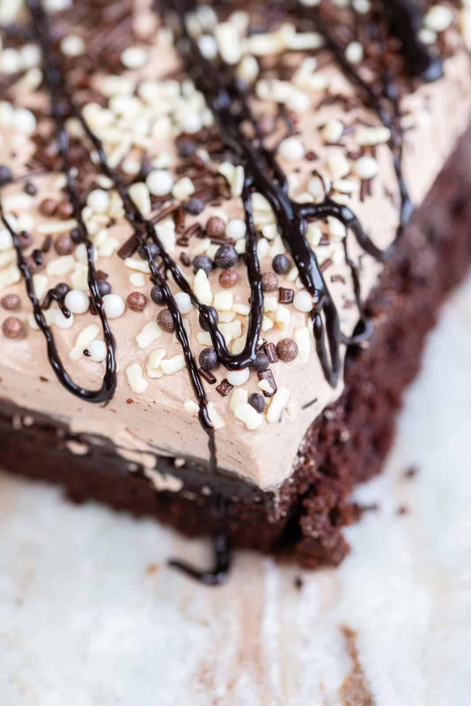Chocolate poke cake frosted with whipped cream and dusted with chocolate sprinkles