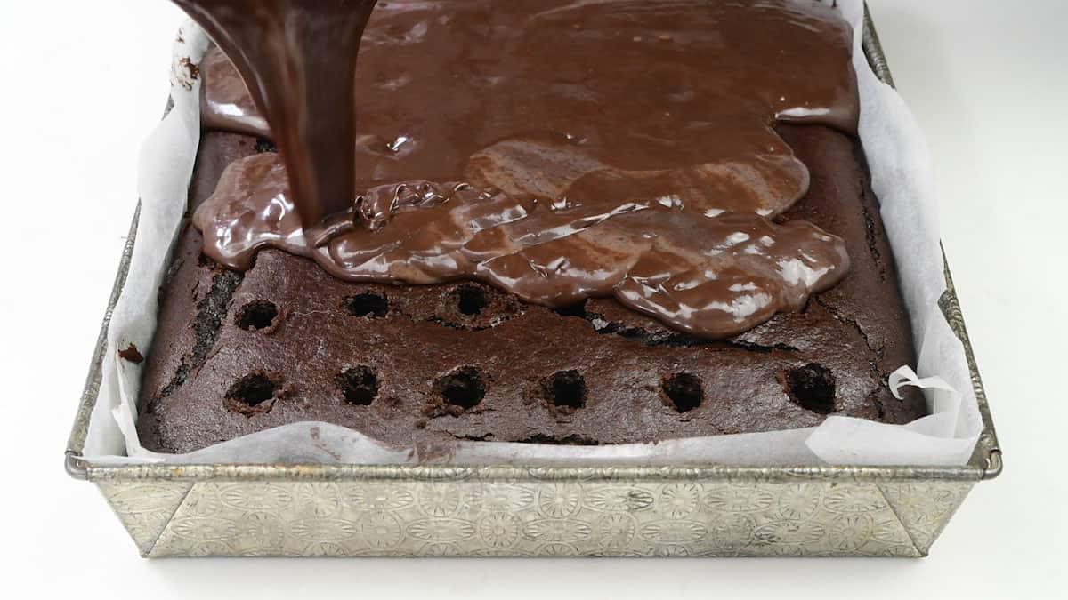 pouring chocolate pudding over poke cake