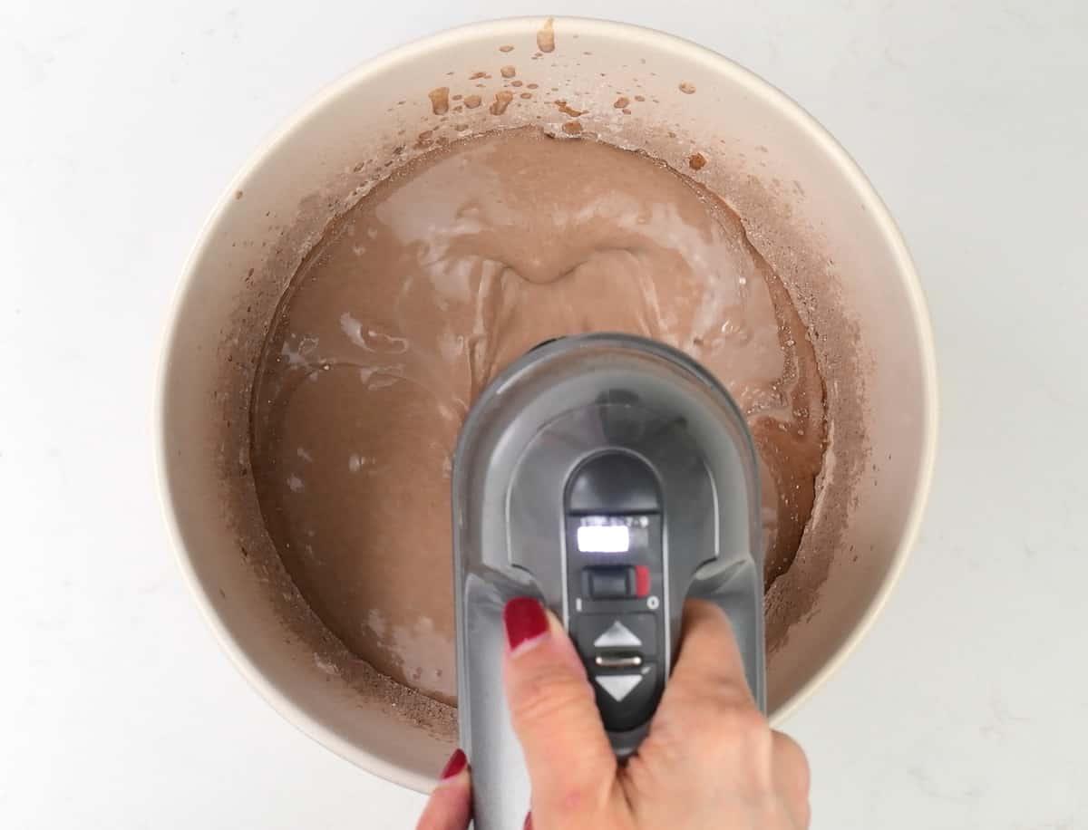 making whipped cream frosting in a bowl with a hand mixer